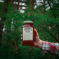 Hand holding O'Donnell Moonshine Blood Orange in woods